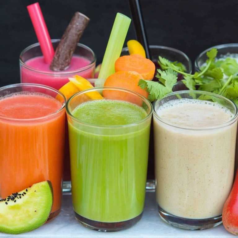 Homemade beetroot and carrot juice in a jar with fresh ingredients on a kitchen counter.