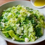 Maroulosalata Greek lettuce salad topped with feta and dill, lemon dressing about to be poured